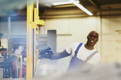 male looking away while operating a machine in a warehouse.
