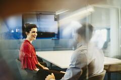 Man and woman in an office having a meeting. Primary color: white.