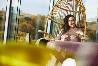 Woman smiling looking away while sitting down and holding her phone.