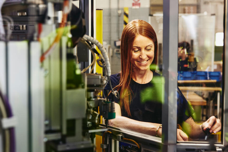 Smiling female operating a machine on a production site